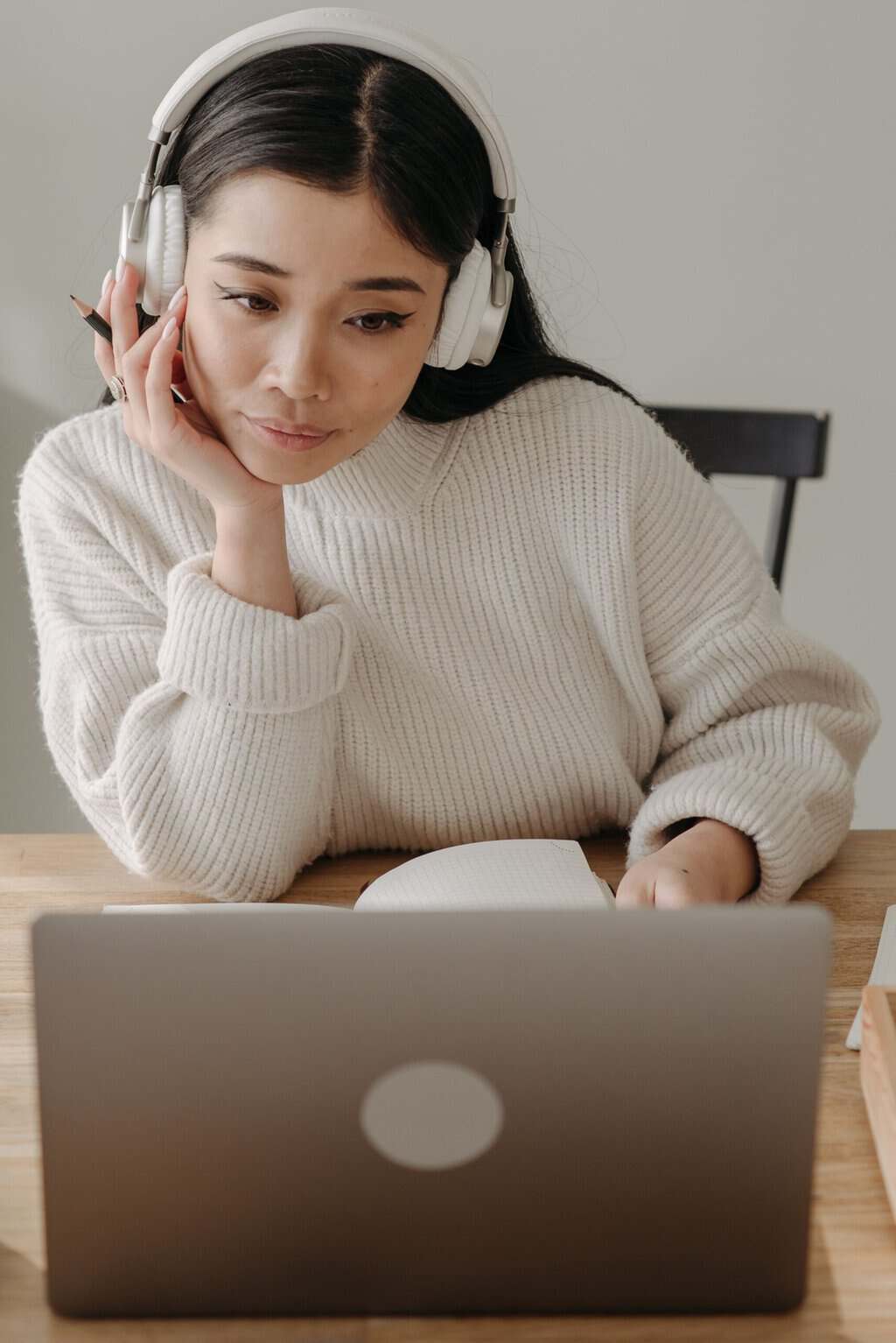 Woman wearing headphones working intently on a laptop indoors.